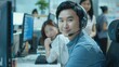One joyful young Asian male contact center telemarketing agent using a headset in an office. Friendly, confident businessman consultant running a helpdesk for customer and sales support