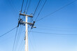 Low angle view of power post and powerlines against a cloudless blue sky. Auckland.