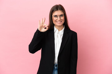 Wall Mural - Young Business caucasian woman isolated on pink background showing ok sign with fingers