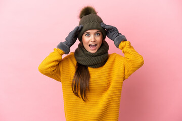 Wall Mural - Young caucasian girl with winter hat isolated on pink background with surprise expression