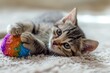 Adorable kitten engages in play, gently kneading a vibrant yarn ball on a cozy surface