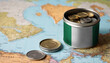 A jar filled with cash, displaying the Nigeria flag, sits atop a map. Saving for vacation, leisure activities. Financial planning, travel budget allocation