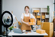 © Nuttapong punna - Young business owner woman prepare parcel box and standing check online orders for deliver to customer on tablet, laptop
