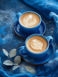 Artistic Latte Art on Two Cups of Coffee with a Blue Background