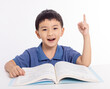 Excited asian child schoolboy studying  at home and hand pointing up