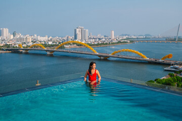 Asian people relaxing in the swimming pool with Han River view and Dragon Bridge in  Da Nang , Vietnam