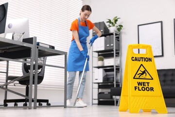 Canvas Print - Cleaning service worker washing floor with mop in office, focus on wet floor sign