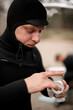Young male surfer wearing a wetsuit scoops up a jar of water repellent cream to apply to his face