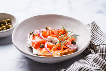 Canvas Print - Breakfast bagel with salmon, cream cheese, capers and onions, white background.