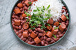 Plate of red beans with sausage and white rice, horizontal shot on a grey granite surface, middle closeup