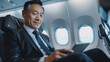 © Anna - Focused businessman on private jet reviewing data on tablet.