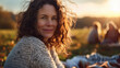 © Anna - Smiling middle-aged woman with curly hair enjoying sunset in nature.