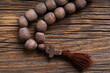 Church rosary for prayer close-up. Wooden church rosary with a cross on a dark wood background.