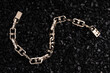 Gold bracelet on a background of black volcanic stones. Beautiful chain bracelets on black background. Gold links hand bracelet.