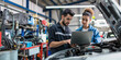 © pilipphoto - Auto mechanic working on laptop while running car diagnostic with his coworker in auto repair shop