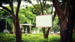 A blank white sign with a red border hangs from a hook in a serene park, surrounded by rich greenery and trees.
