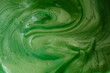 Closeup of green fluid metallic acrylic paint textured background