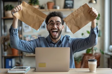 Wall Mural - An excited Middle Eastern man in casual attire, sitting at an office desk with his laptop open and holding up documents to the camera, exuding happiness while celebrating success or winning happily. 