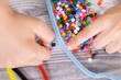 Preschooler hands with creative sticks and beads used to making bracelets. Development of kids motor skills, coordination and logical thinking