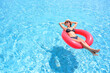 Summer vacation concept. Young beautiful woman in bikini wear hat and sunglasses relaxing in swimming pool with rubber ring.