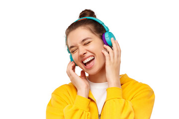 Wall Mural - Horizontal banner of young happy girl dressed in yellow hoodie and having fun while listening to music in wireless headphones, isolated on pink background with copy space