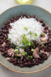 Plate of black beans served with rice and chicken meat, vertical shot, selective focus, close-up