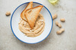 Blue and white plate with peanut butter and toasted bread, above view on a beige stone background, horizontal shot