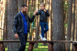 Father and son walking hand in hand on a pedestrian obstacle course in the forest, cute boy looking at his dad