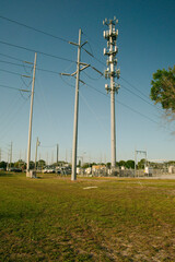 Vertical view near sunset of Electric Substation with High Power Lines in St. Petersburg, Florida. Utility trucks.View over green grass, blue sky  with large metal utility poles. No People. Copy space