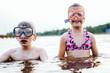 © Iryna - Two smiling friends splashing with water at lakeshore wearing swim masks to learn to swim. Summertime children healthy vacation concept.