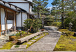A footpath through a park with pine trees and houses in kyoto