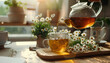 Female hand pouring natural chamomile tea from teapot into cup on table in kitchen