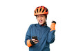Young cyclist girl over isolated chroma key background with phone in victory position
