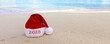New Year 2025 background with red Santa hat on Caribbean beach.