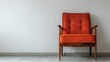  A room features an orange chair contrasting against a large white wall The floor is tiled
