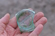 hand holding one green glass sharp piece of old broken bottle on the street