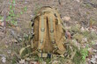 one brown army backpack standing on a earth outdoors in nature