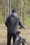 Fototapeta Desenie - one man in a black jacket stands with his back and holds a bicycle on the street in nature