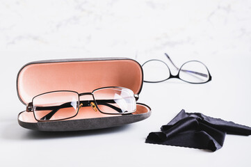 Wall Mural - Eyeglasses in an open hard case and a cleaning cloth in front of other glasses on a table