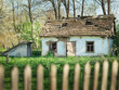 old abandoned farm house behind wooden fence in Ukrainian village