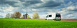 panorama with green field and white camper bus