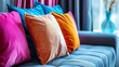   A blue couch is home to a vibrant row of pillows, each adorned with distinct colors Nearby, a vase displays a solitary flower