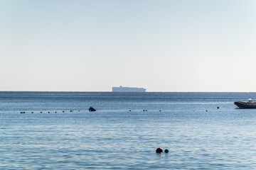 Wall Mural - Calm blue sea with the silhouette of a large ship on the horizon