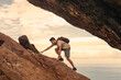 Man hiking climbing up mountain cliff, never give up, people determination,  perseverance, reaching your goals 