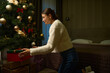 Side view of young woman putting gift box under christmas tree during Christmas