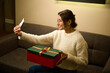 Pleased woman taking selfie on smartphone of herself with gift during Christmas