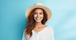 Summer portrait of beautiful happy smiling young woman in straw hat posing on blue background