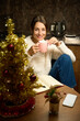 Woman drinking tea or coffee and looking at camera at table during Christmas