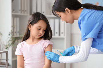 Canvas Print - Little Asian girl receiving vaccine in clinic