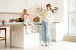 © Pixel-Shot - Nanny with little girl blowing soap bubbles in kitchen
